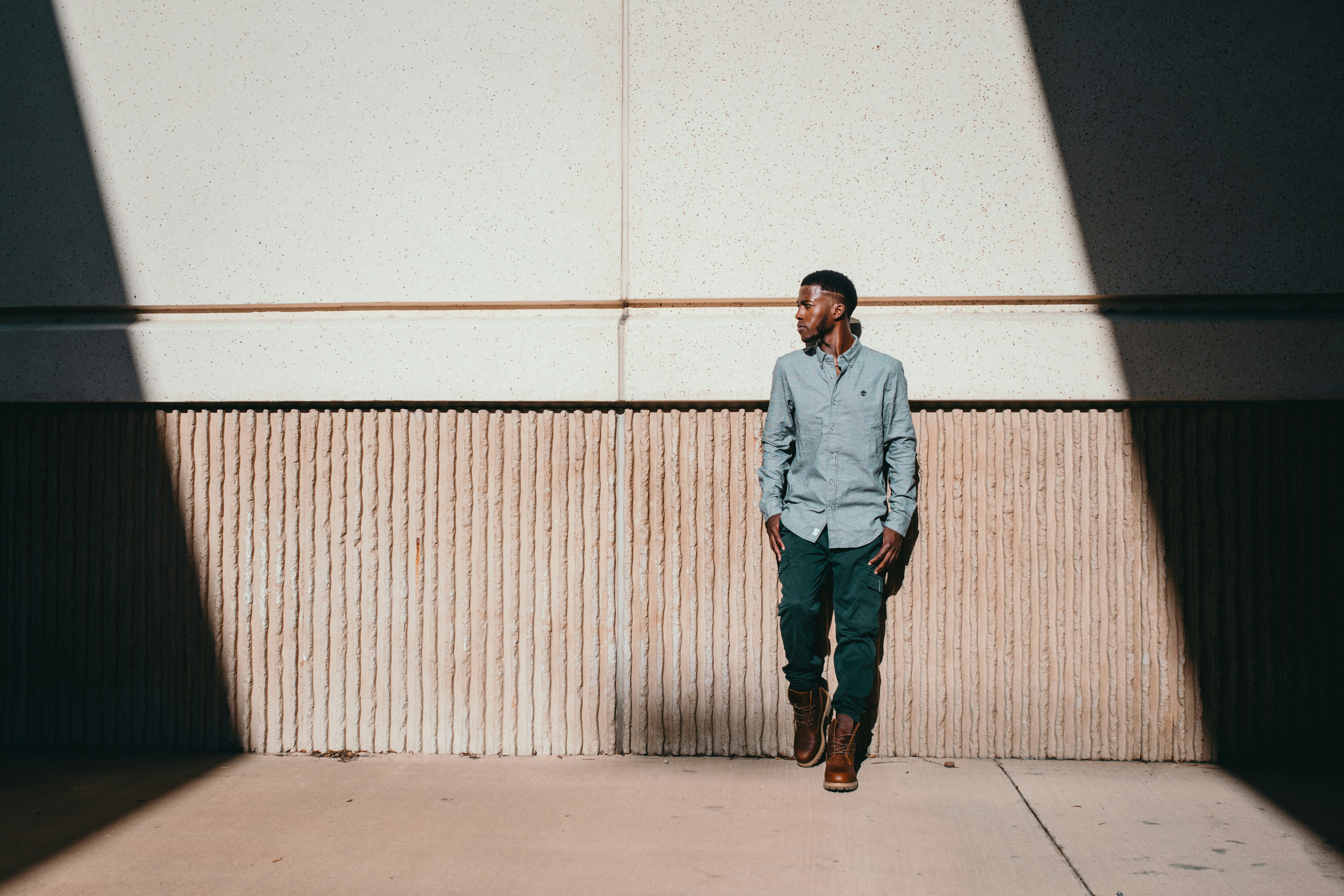 man leaning on white wall